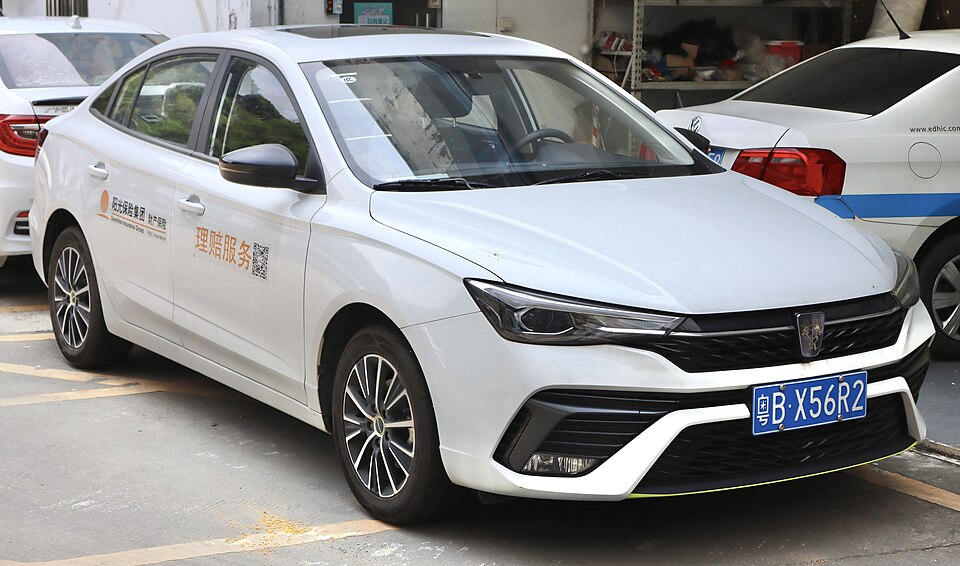 A small front-engined four-door car with a three-box design with alloy wheels, door mirrors, a front grille, stylised headlights, front fog lamps, and a sunroof.